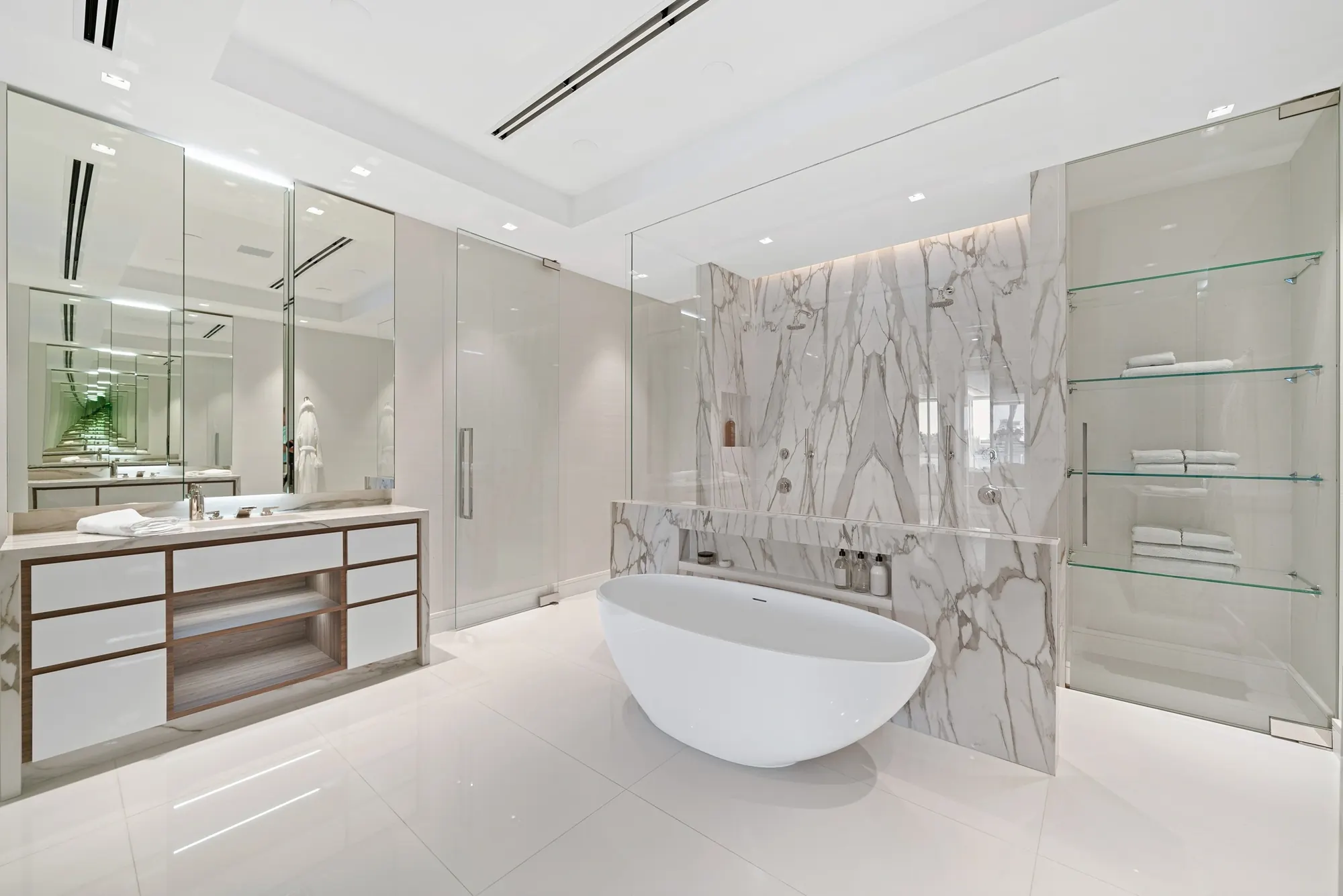 Primary bath with glass-enclosed shower and marble wall