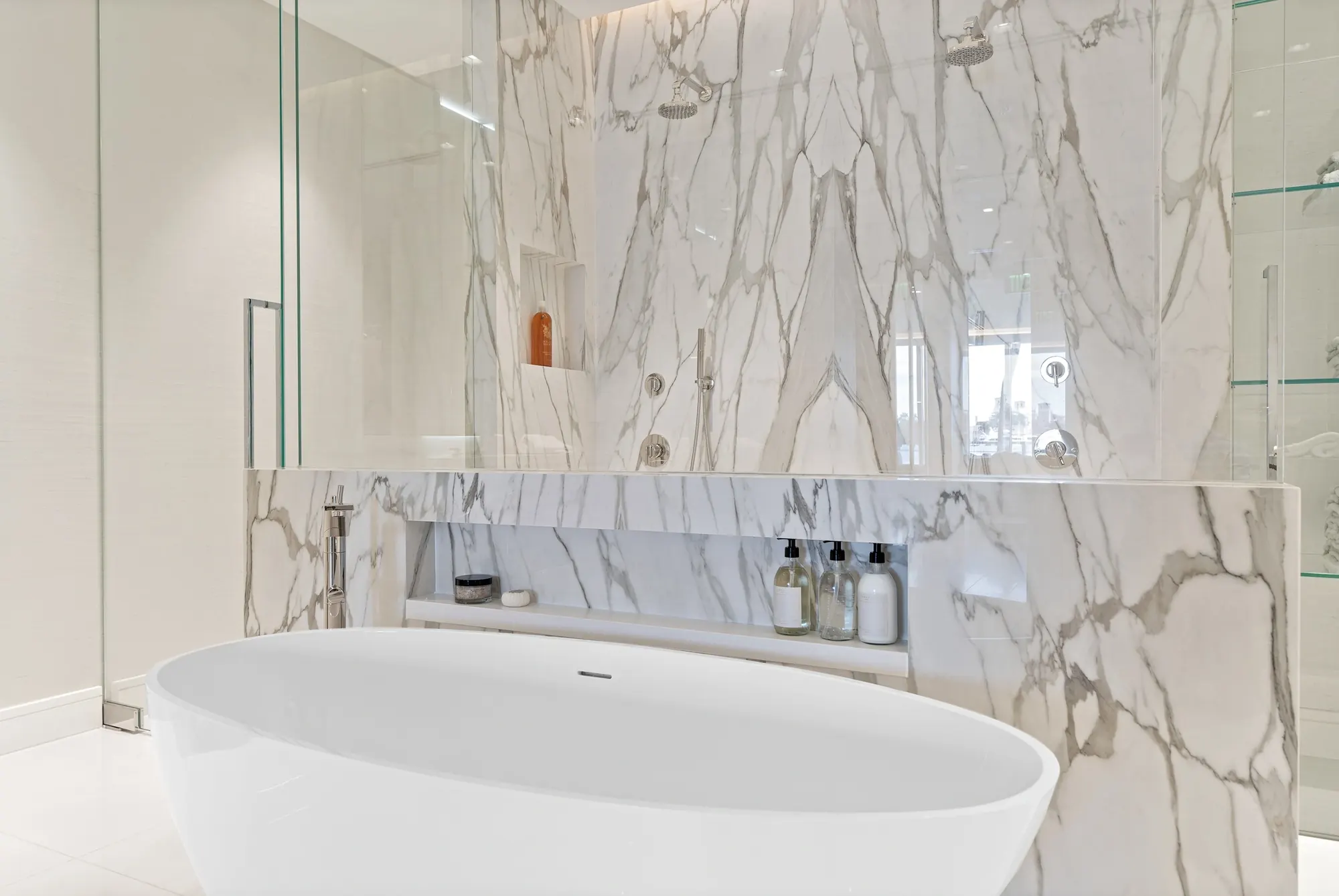 Freestanding tub against a marble wall